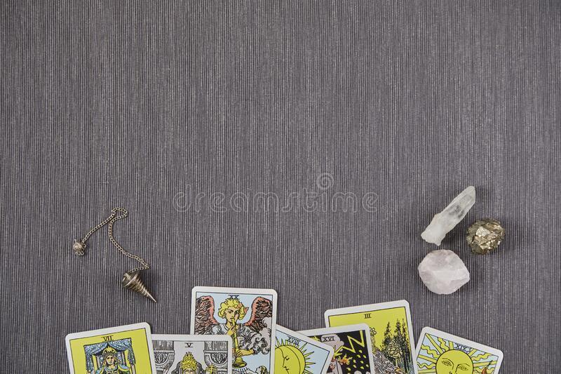 cartes-en-bas-arcane-majeure-tarot-trois-quartz-rose-blanche-et-pendule-métallique-fond-de-tissu-gris-233859600